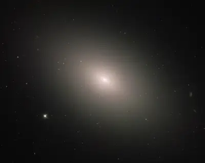 Hubble-Aufnahme der elliptischen Galaxie M59 mit hellem Kern und zahlreichen Kugelsternhaufen
