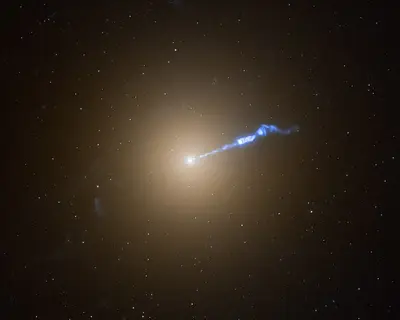 Die elliptische Riesengalaxie M87 (Virgo A) als heller diffuser Lichtball, aus dem ein schmaler blau leuchtender Plasmajet herausschießt